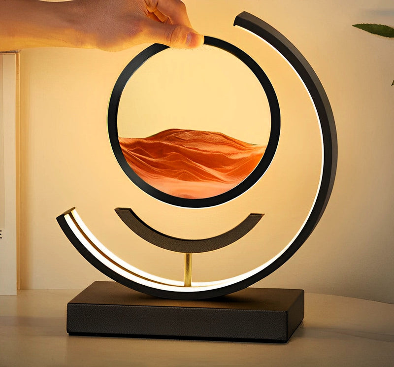 Modern table lamp with a circular design and mountain landscape inside, on a neutral background.